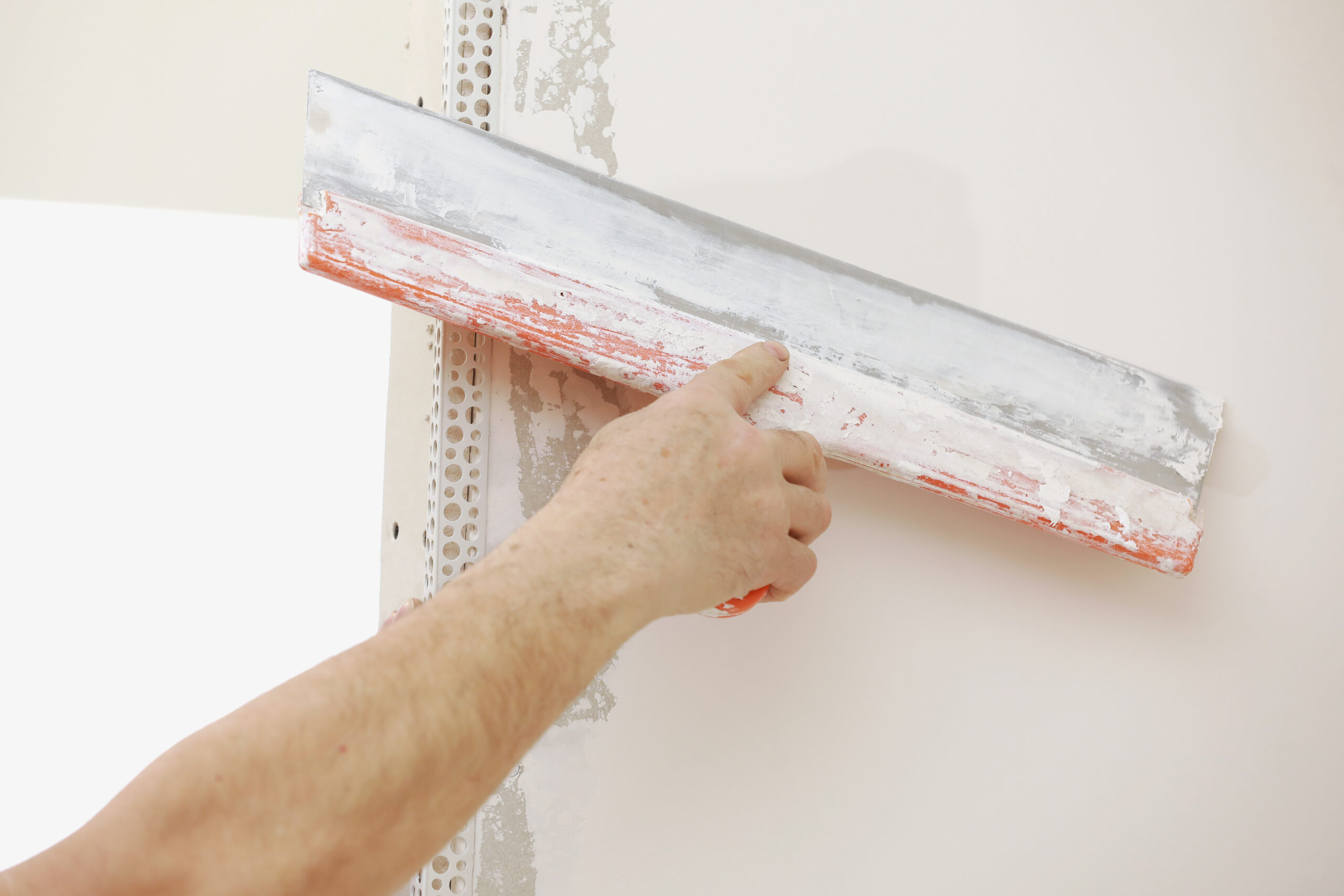 Worker applying smooth float finish plaster coat on interior wall